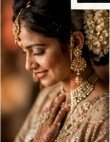 Close-up of joyful bride looking down with jasmine gajra and golden necklace