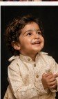 Smiling child clapping in cream silk ethnic attire during family celebration portrait